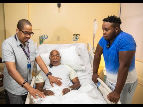 Dr Roger Hunter (left) speaks with patient Delroy Ricketts (centre) and his son David before the surgery.