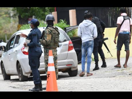 Members of the security forces, man a checkpoint on St John’s Road in St Catherine. 