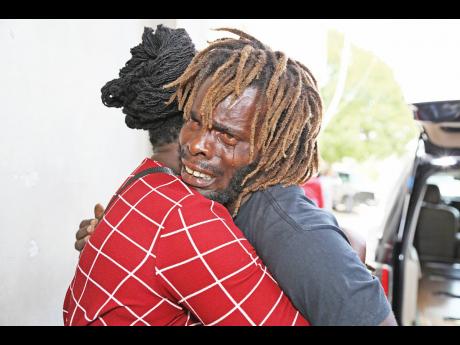Owen Tomlinson, father of three-year-old Abigail and four-year-old Kayla, is consoled by a family friend at the funeral for his daughters at Race Course Seventh-day Adventist Church on Sunday. The girls died in a house fire in Race Course, Clarendon, in March. The children’s mother has been charged with negligence. 

