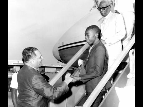 Jason Whyte (centre) being welcomed back to Jamaica by Allan Douglas, minister of youth and community development, at the Palisadoes Airport. Oscar Savage, Jamaican consul in Panama, who accompanied Jason on a TACA flight from Panama, is behind him.