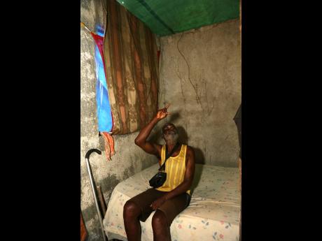 Leroy Manning points to the tarpaulin roof, which leaks whenever it rains.