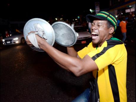 A Jamaican celebrates in the streets of Half-Way Tree, St Andrew, after Elaine Thompson won  the women’s 200 metres at the 2016 Olympic Games in Rio, Brazil.