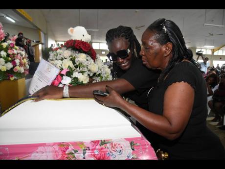 Relatives of the Clarendon five Jassian McKnight (left) and Leonora White cry over one of the caskets at the funeral on Sunday.