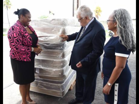 Credit: Ian Allen Minister of Labour and Social Security, Karl Samuda (centre), Permanent Secretary in the ministry, Colette Roberts Risden (right) and Community Relations Manager at the Early Childhood Commission (ECC), Tanisha Miller look at mattresses handed over to the ECC for distribution to early childhood institutions across the island. The handover took place at the ministry’s facility on Marcus Garvey Drive in St Andrew on Wednesday.