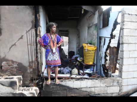 Credit: Ricardo Makyn Ricardo Makyn/Chief Photo Editor
A distraught Sophia Grant stands at the entrance of what remains of her home following a massive fire between Smith Lane and James Street in central Kingston.