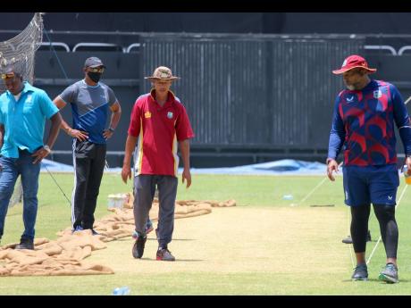 Head curator Michael Hylton (third from left) surveys the Sabina Park pitch along with West Indies head coach Phil Simmons (right) yesterday.