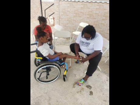 Occupational therapist Farah Augustin (right) from Global Hands Foundation treats Tamara Noble at the health fair in Bounty Hall, Trelawny. Looking on is Tamara’s mother Stacy-Ann Reeves-Noble.