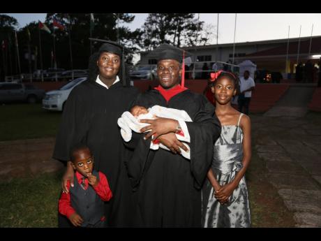 Marvin Pryce celebrates with his wife Kadiann Edwards-Pryce after they both graduated from Northern Caribbean University on Sunday. Celebrating the occasion are their children Jeremiah (left), Amora (right) and baby Kayla-Ann. 