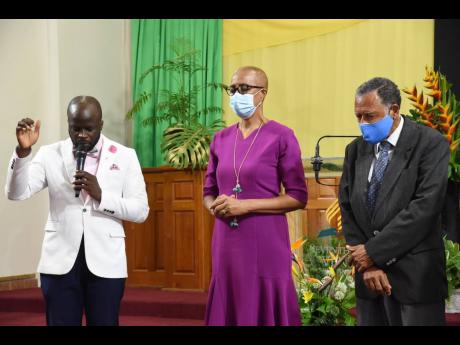 Credit: Contributed Education and Youth Minister Fayval Williams (centre) and elder at the Andrews Memorial Seventh-day Adventist Church, Noel Jump (right), show reverence as Pastor Omar Oliphant delivers the prayer during a service held on Saturday at the church’s Hope Road location in St Andrew.