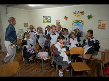 Schoolgirls listen to their teacher as they sit in a bomb shelter on the first day of school at a cadet lyceum in Kyiv, Ukraine on Thursday. 