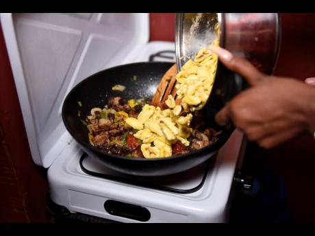 Credit: Nicholas Nunes/Photographer STAR Foodie Shanel adds the ackee to the seasoned jerk pork.