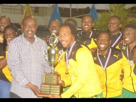Jamaica’s male netball captain Kurt Dale (right) collects the winning trophy from Fredrick Stephenson, minister of public service, consumer affairs and sports of St Vincent and Grenadines, after Jamaica Suns topped the Americas Netball Championships on Sunday. 