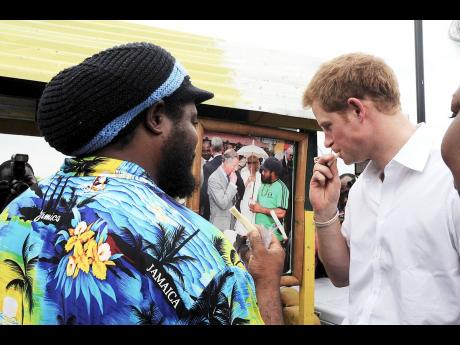 Vendor Carlos Morgan (left) of Falmouth, Trelawny, shows Harry a photograph he took with his father, Prince Charles, as he ate a piece of the sweet treat during a 2008  visit to the town. 