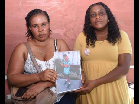 Georgia Adams (left), mother of six-year-old Jevanie Kidd, and Karen Carty, hold a picture of young Jelanie, who drowned after being washed away by floodwaters in Catadupa, St James, on September 8.