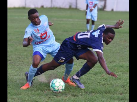 Jaheem Frazer (right) of Jamaica College is bundled off the ball by St Catherine High’s Rolando Redman during their ISSA/Digicel Manning Cup football match at the Spanish Town Oval on Friday. The match ended 0-0 and St Catherine will face neighbours St Jago at the same venue today.