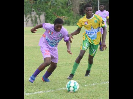 Irwin High’s Leo Campbell (left)  and Green Pond High’s Matthew Ellis battle for possession during yesterday’s ISSA/Digicel daCosta Cup football match at the Irwin High Sports Complex. Irwin High won 2-0.