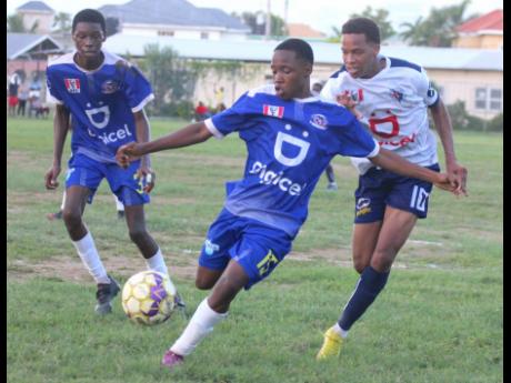 Cedar Grove’s Roshawndo Roman (left) attempts a clearance as Jamaica College’s (JC) Kevaughn Wilson (right) presses during their ISSA/Digicel Manning Cup Group B encounter at Cedar Grove Academy in Portmore yesterday. Cedar Grove’s Charles Reid watches in the match which JC won 4-0.