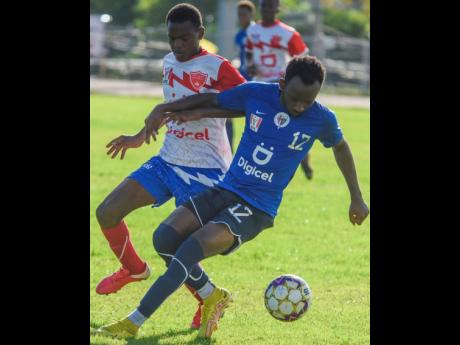 Kimarley Graham (left) of Holy Trinity moves in to tackle Jamaica College’s (JC) Michael Graham during their ISSA/Digicel Manning Cup match at Ashenheim Stadium on October 11. JC demolished Holy Trinity 9-0.