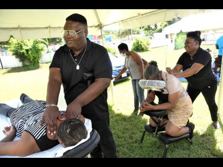 Jerome Jackson (left) gives a massage at the Jamaica Society for the Blind health fair on Thursday.