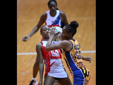 
American Aniyah Lamgiagne (left) takes evasive action as Barbados’ Akeema Stoute collects a pass during their Americas Netball World Cup qualifier at the National Indoor Sports Centre last night.