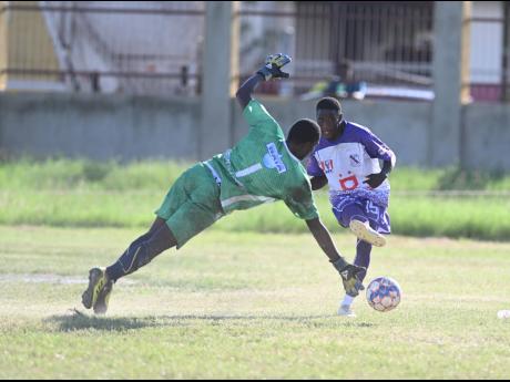 Kingston College’s Nashordo Gibbs (right) shoots at goal, which Waterford High’s goalkeeper Alphanso Salmon tries to block in their ISSA/Digicel Manning Cup match at Waterford yesterday. Gibbs scored a brace as KC won 2-0.