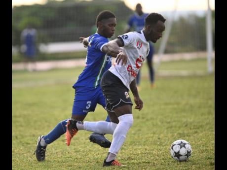 Jamaica College’s (JC) Michael Graham (right) dribbles past Norman Manley High’s Deshawn Thomas during their ISSA/Digicel Manning Cup football match at Calabar High yesterday. JC won 5-0.