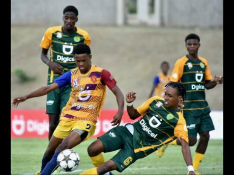 St Andrew Technical High School’s Shakeone Satchwell (left) tries to evade a challenge from St Jago High School’s Brandon Solomon during their ISSA/Digicel Manning second-round tie at the Stadium East on Friday. St Jago won 1-0 but STATHS progressed on the away-goal rule, after winning the first-leg 2-1.