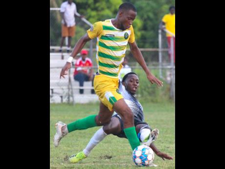 Vere United’s Jahmar Wright (left) tries to evade a sliding challenge from Cavalier’s Dwayne Allen during their Jamaica Premier League (JPL) encounter at the Wembley Centre of Excellence in Clarendon, yesterday. Cavalier won 3-0.