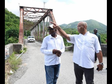 James Robertson (right), member of parliament for St Thomas Western, giving Everald Warmington, minister without portfolio in the Ministry of Economic Growth and Job Creation a tour of sections of the constituency.