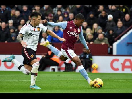 Aston Villa's Leon Bailey (right) scores the opening goal during the English Premier League  match between Aston Villa and Manchester United at Villa Park in Birmingham, England on Sunday. At left is Manchester United's defender Lisandro Martinez.