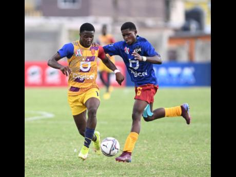 Credit: Ricardo Makyn St Andrew Technical High’s (STATHS) Omar Reid (left) dribbles clear of Dejaun Green of Wolmer’s Boys during yesterday’s Manning Cup quarter-final match at the Stadium East field. STATHS won 1-0.