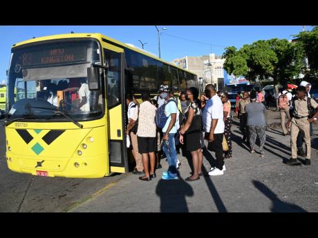 Credit: Rudolph Brown Commuters board a Jamaica Urban Transit Company bus in downtown Kingston as public passenger vehicle operators went on strike, demaning a traffic ticket amnesty.