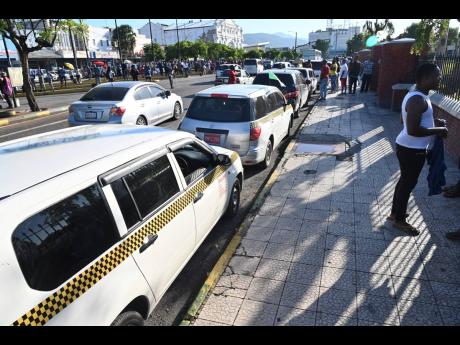 Credit: Rudolph Brown Taxi drivers line up at North Parade in downtown Kingston yesterday.