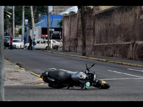 A police service motorcycle lies at the intersection of East and East Queen streets in downtown Kingston. The cop, who was driving the motorcycle, was shot and injured by cowards.