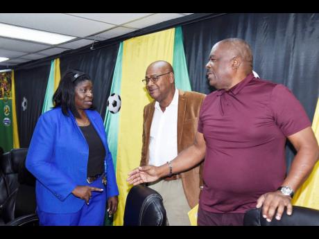 Chairperson for women’s football in Jamaica, Elaine Walker-Brown (left) has the attention of president of the Jamaica Football Federation (JFF), Michael Ricketts (centre) and vice-president Raymond Anderson during the launch of the Women’s Premier League yesterday.