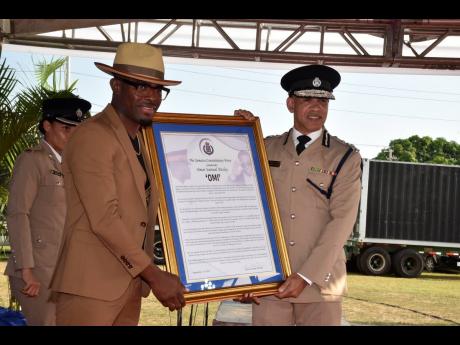 Commissioner of Police, Major General Antony Anderson (right) hands Omar ‘OMI’ Pasley, international recording artiste and former member of the Jamaica Constabulary Force (JCF) with a citation in his honour at the JCF Long Service and Good Conduct award ceremony at the Police Officer’s Club on Hope Road, St Andrew on Thursday.
