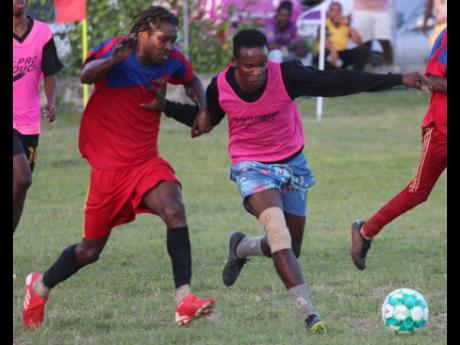 Kemar Golbourne of Treadways (left) tussles for possession with Akeel Buckley of March Pen ‘A’ during the final of the football competition of the SDC Four-In-One competition at the March Pen Community Centre recently.