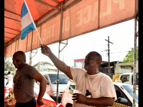 Credit: Kenyon Hemans Argentina supporter Wayne (right) shows his support by waving the flag as he watched the match against Mexico at Sonia’s Place on the Terrace on Waltham Park Road in St Andrew on Saturday.