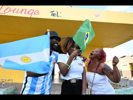 Cheers to the Cup co-host Shanel Lemmie (centre) gets an earful from Argentina supporters, co-host Roxroy McLean and Asheena Bryan, outside the Dat A True Bar in Tivoli Gardens, following the team’s win over Poland yesterday.