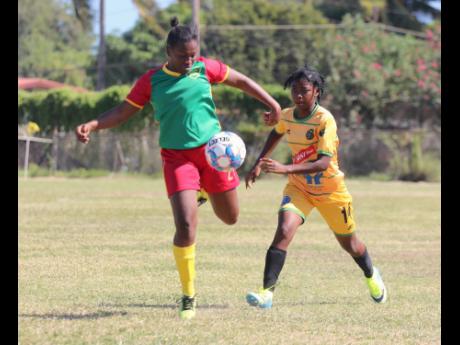 Real MoBay AFC player Zenesha Williams (left) gets ready to make a clearance ahead of a challenge by Vere United’s Jully-Ann Howard during their Jamaica Women’s Premier League (JWPL) encounter at the Wembley Centre of Excellence yesterday. Vere won 11-0.