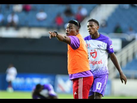 Kingston College head coach Raymond Watson (left) issuing instructions to Dujuan ‘Whisper’ Richards during a Manning Cup  match. 