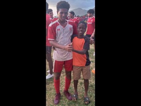 Campion College’s Kai Myles (left) poses with a young fan after scoring their goal in the 1-0 win over St George’s College in the Colts (under-16) final at Calabar yesterday.