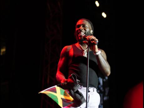 Burna Boy waves a Jamaican flag on stage during his performance at the National Stadium early Monday morning.