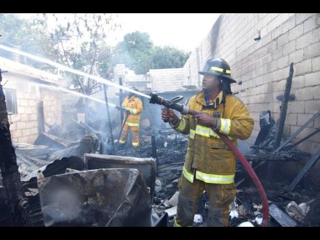 Firefighters conduct cooling-down operations at a dwelling on Cleveland Road in east Kingston on Thursday. Arson is suspected.