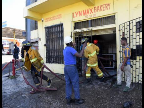 Firemen moving their equipment from Lyn Max Bakery along Slipe Road in Kingston after extinguishing a blaze in the upper part of the establishment.