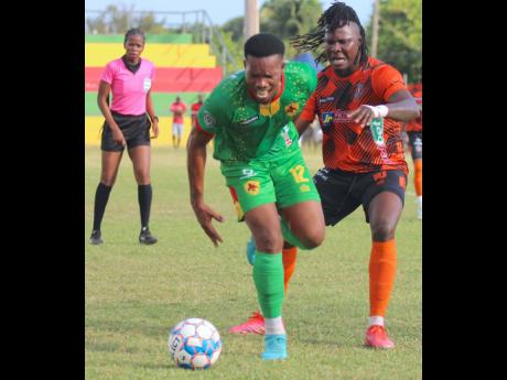 Humble Lion midfielder Andrew Vanzie (left) is clipped from behind by Tivoli Gardens midfielder Rodico Wellington during their Jamaica Premier League (JPL) encounter at Effortville Community Centre in Clarendon yesterday. Referee Nerisa Goldson watches the action closely as Humble Lion secured a 1-0 victory.