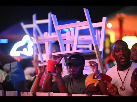 Credit: Gladstone Taylor Patrons shelter under folding chairs.