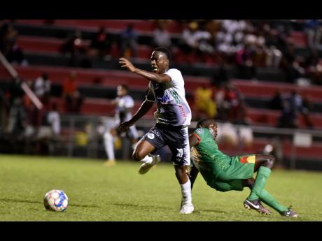 Credit: Kenyon Hemans Dwayne Atkinson (left) of Cavalier gets away from the tumbling Andre Glennon of Humble Lion during their Jamaica Premier League (JPL) match at the Anthony Spaulding Sports Complex yesterday. Cavalier clipped Humble Lion 2-1.