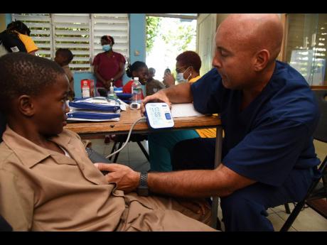 Credit: Ian Allen Michael Chaikel (right), physician assistant, checks the blood pressure of nine-year-old Shavarie Daley.
