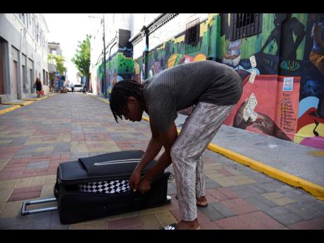 Deshae ‘Bones’ Raphael zips his friend Suede into this suitcase, much to the amazement of onlookers.